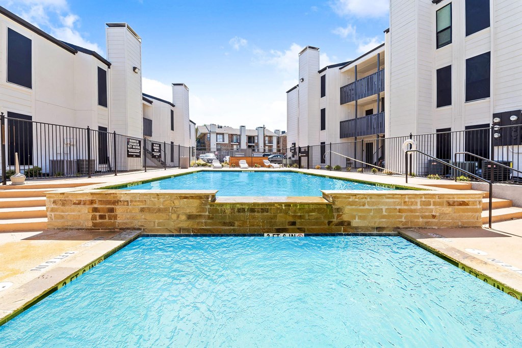 a large swimming pool with apartments in the background