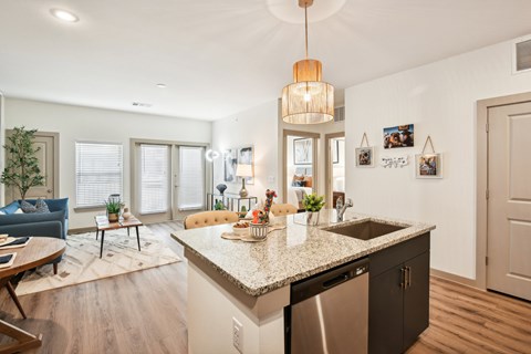A kitchen with a granite countertop and a blue sofa in the living room.