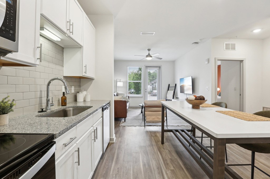 A modern kitchen with white cabinets and a wooden island.