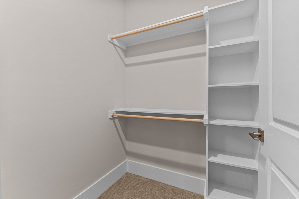 a walk in closet in a home with empty shelves