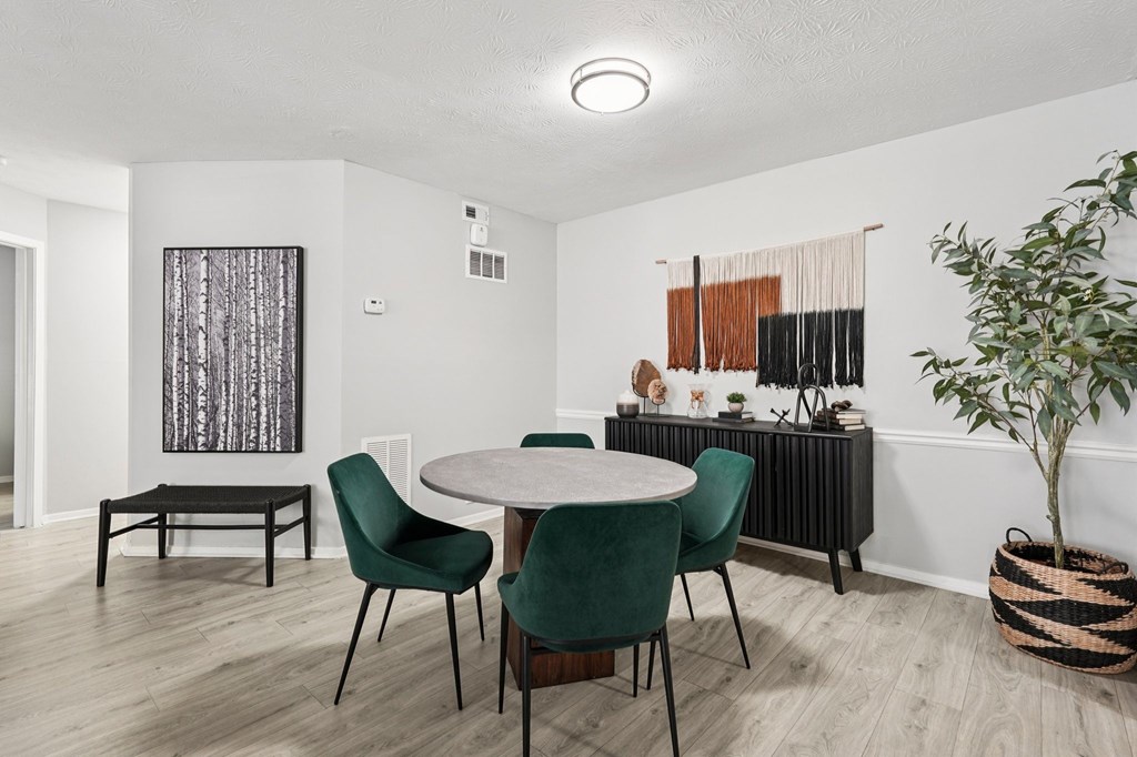 A room with a round table and green chairs.