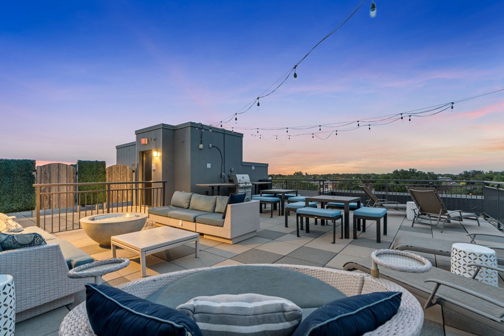 a rooftop patio with couches tables and chairs and a fire pit
