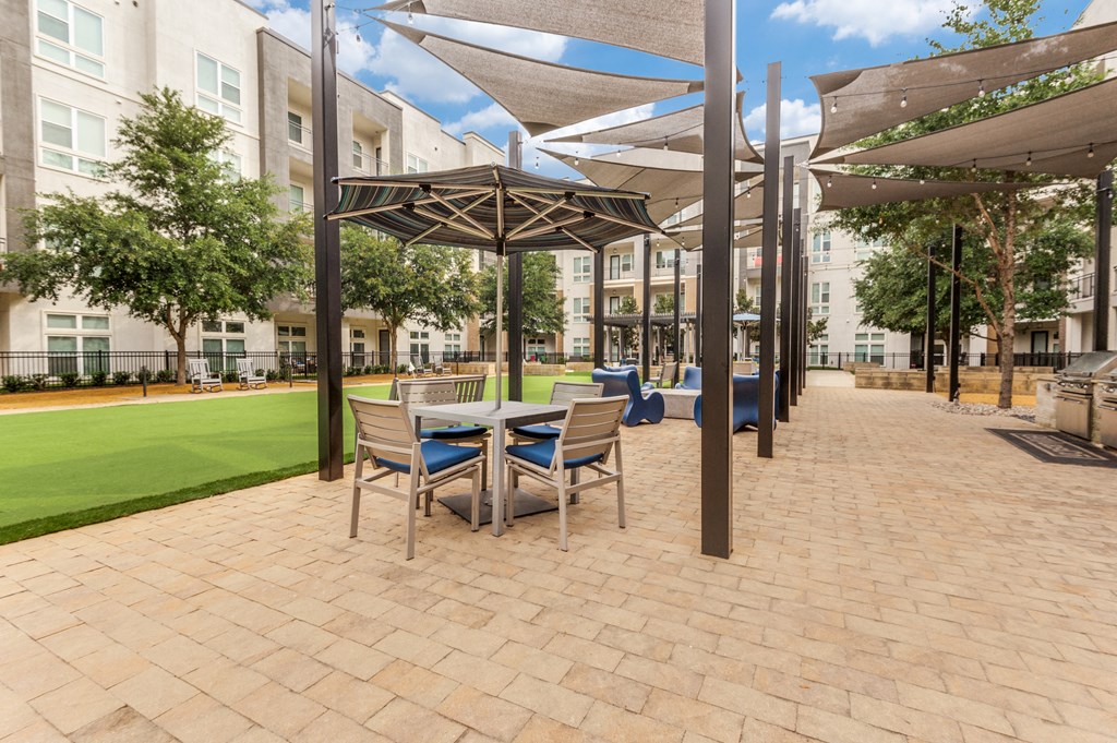 a patio with a table and chairs and umbrellas in front of a building