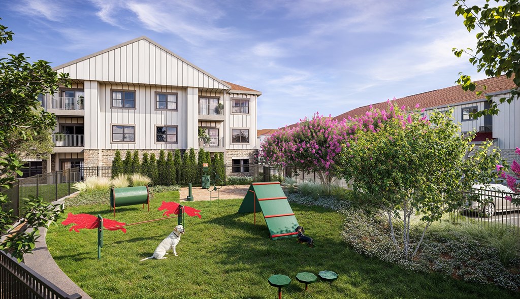 A dog is sitting in the grass in front of a building.