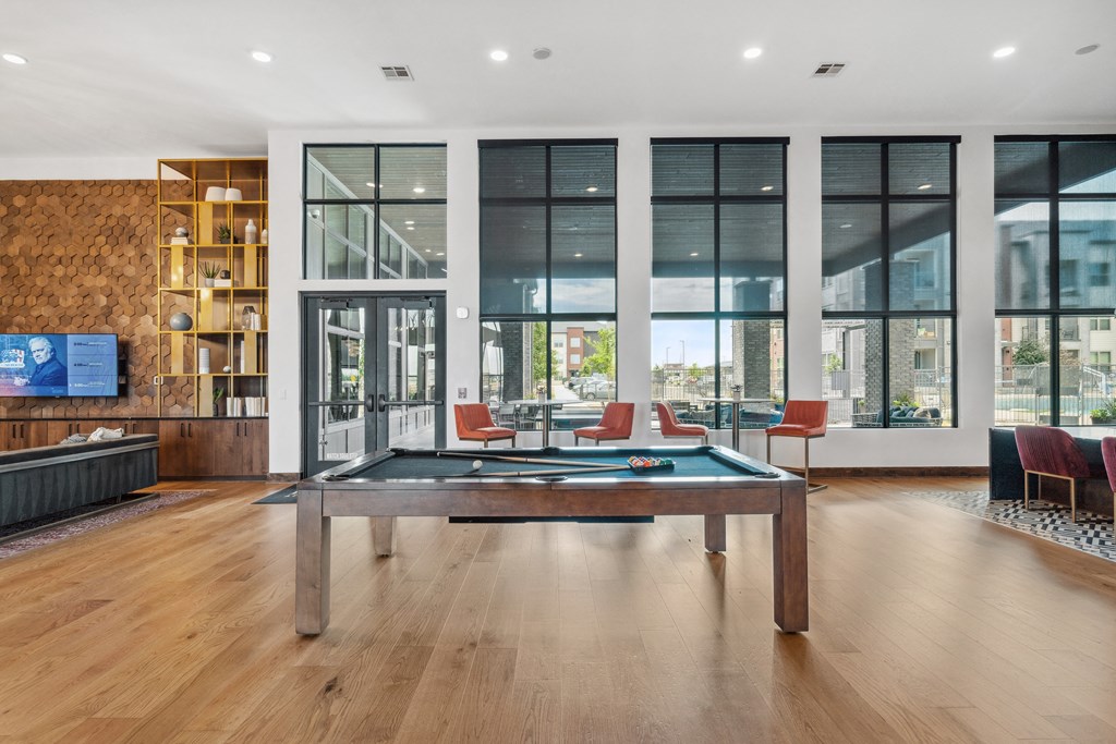 a pool table in a living room with large windows