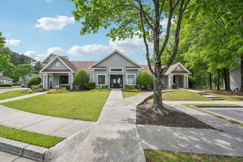 A tree stands in front of a house with a driveway.