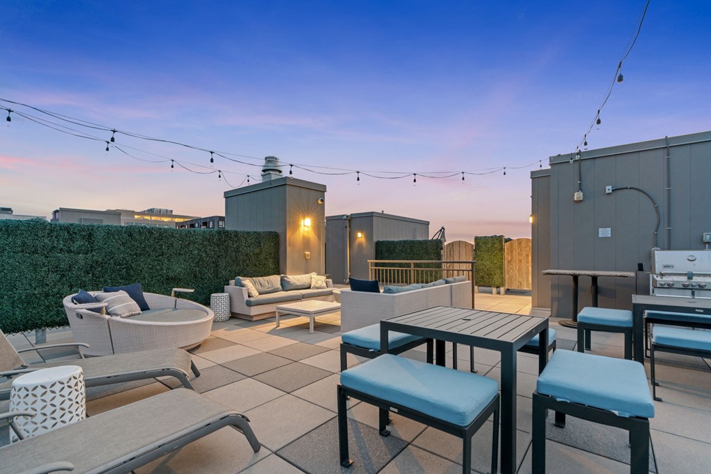 a rooftop patio with tables and chairs and a fire pit