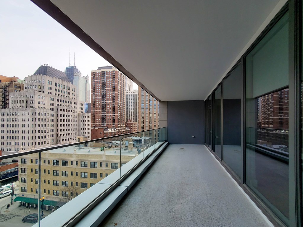 A long, narrow balcony with glass railings overlooks a cityscape.