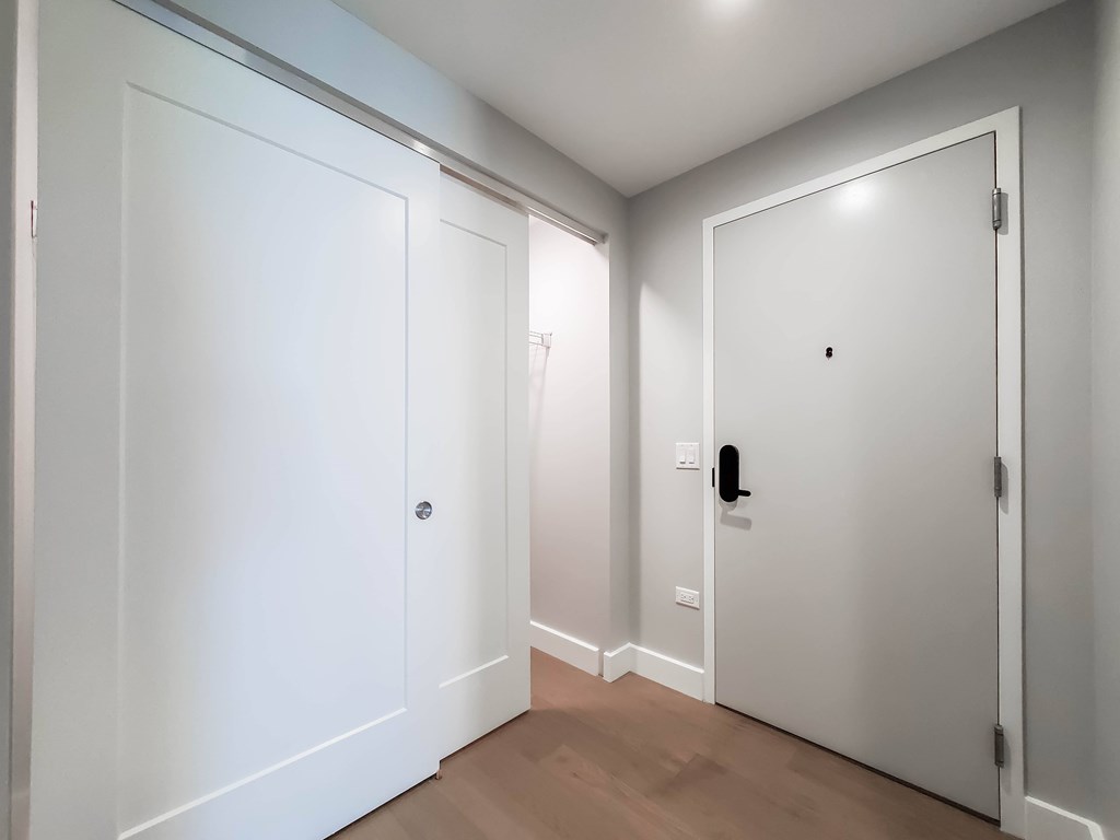 A hallway with two doors and a light switch.