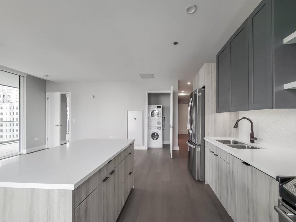 A modern kitchen with white countertops and dark wood floors.