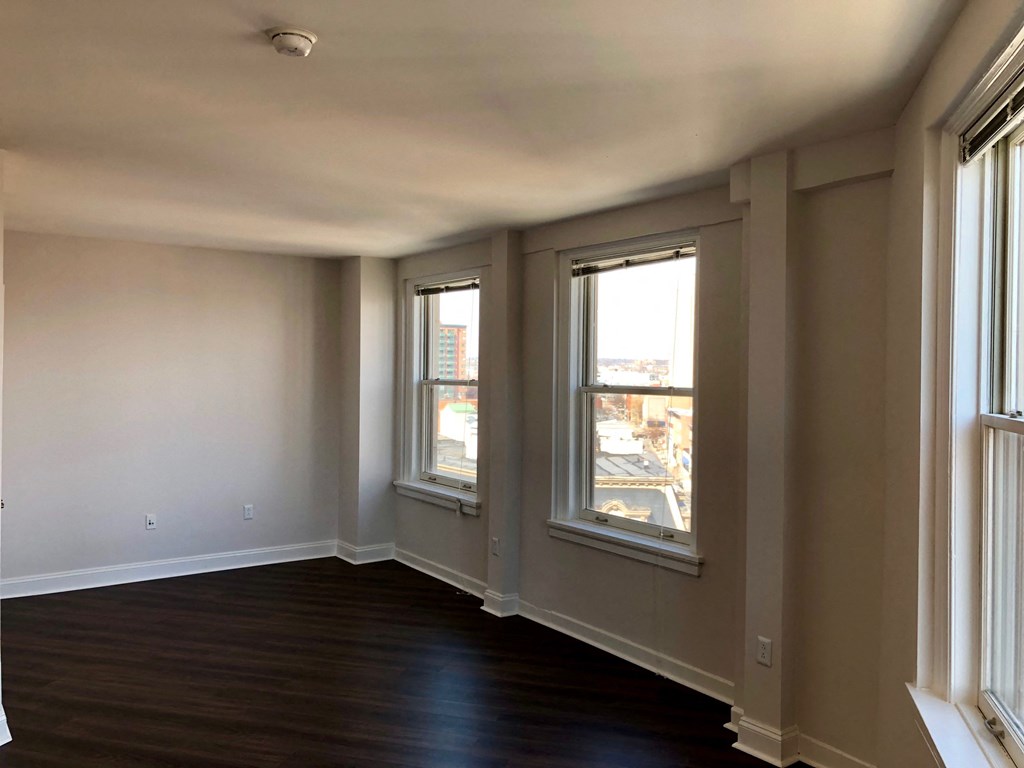 A room with two windows and a wooden floor.