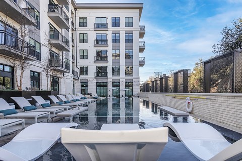 a swimming pool with lounge chairs next to an apartment building