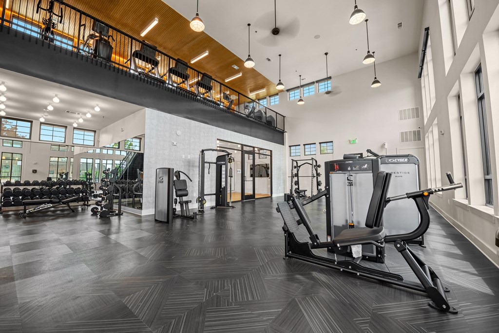a gym with cardio equipment and weights in a building with tall windows