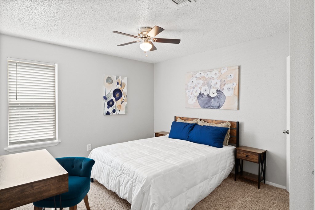 A bedroom with a bed, chair, and painting on the wall.