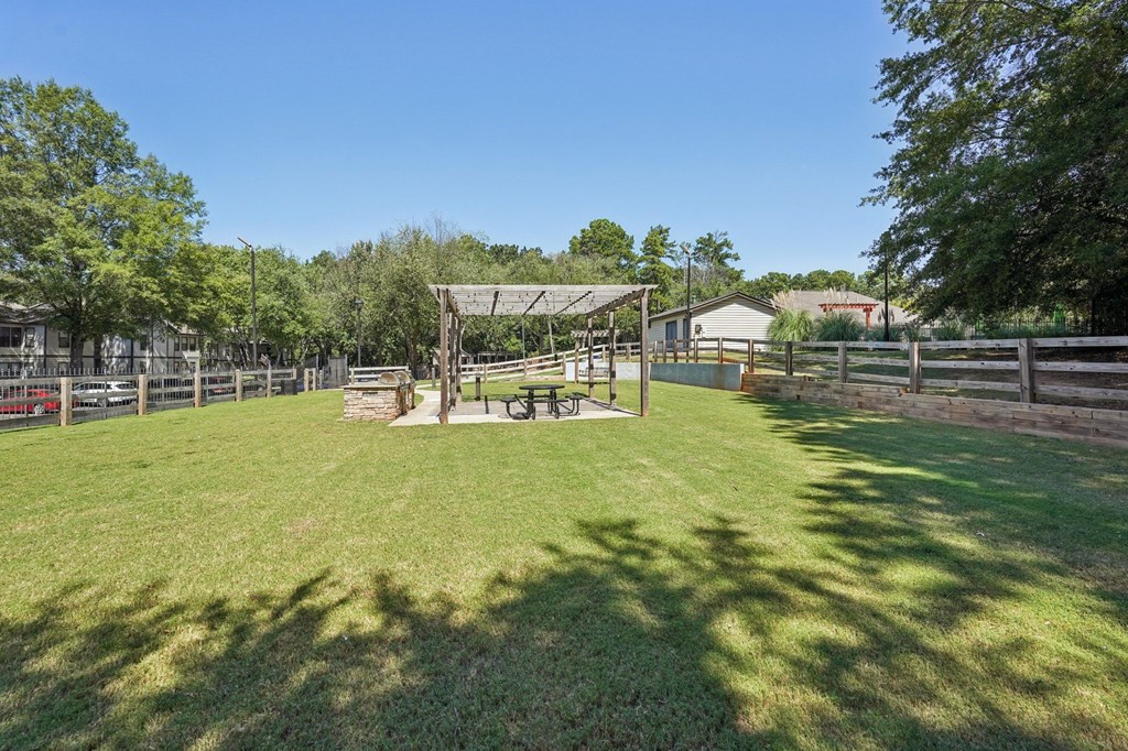 A grassy field with a picnic table and a fence.