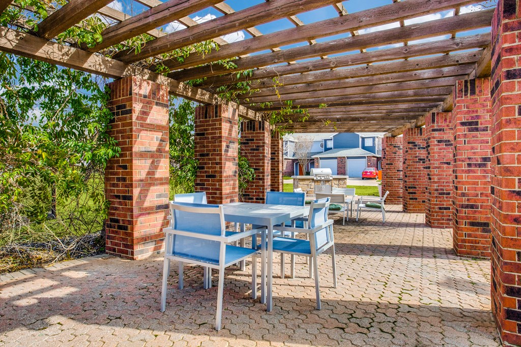 a patio with tables and chairs under a wooden pergola