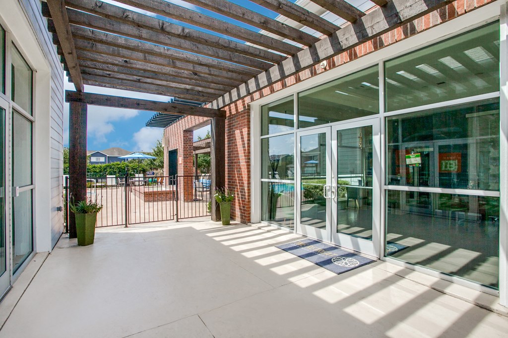 a covered patio with glass doors and a brick building