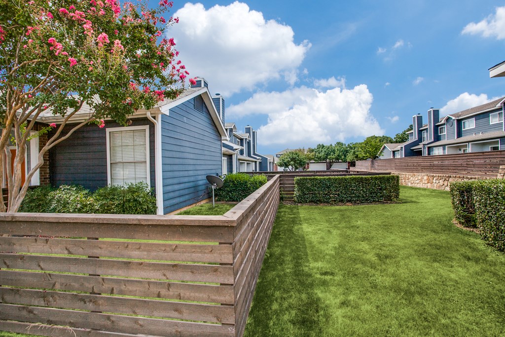 the backyard of a house with a green lawn and a fence