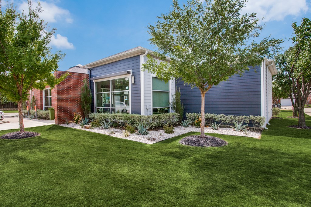 a blue house with a lawn and trees in front of it