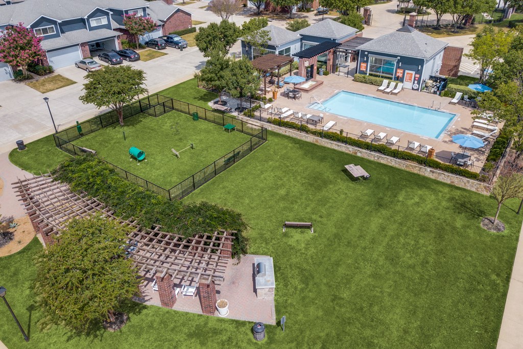 an aerial view of a pool and a yard with lounge chairs