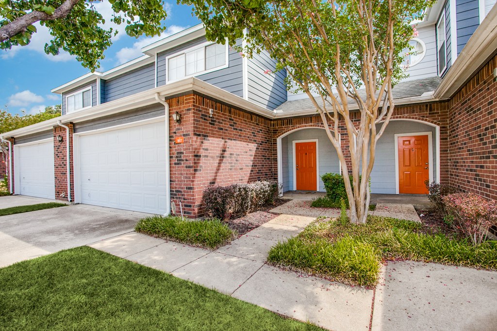 the front of a brick house with an orange door