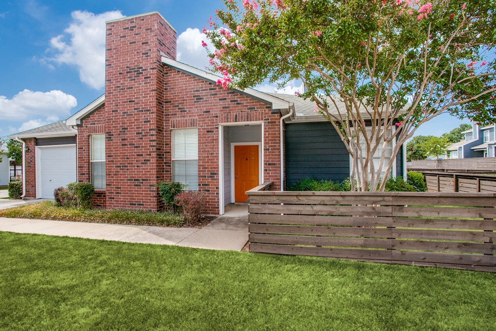 the front of a brick house with a wooden fence