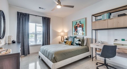 A bedroom with a bed, desk, and chair.