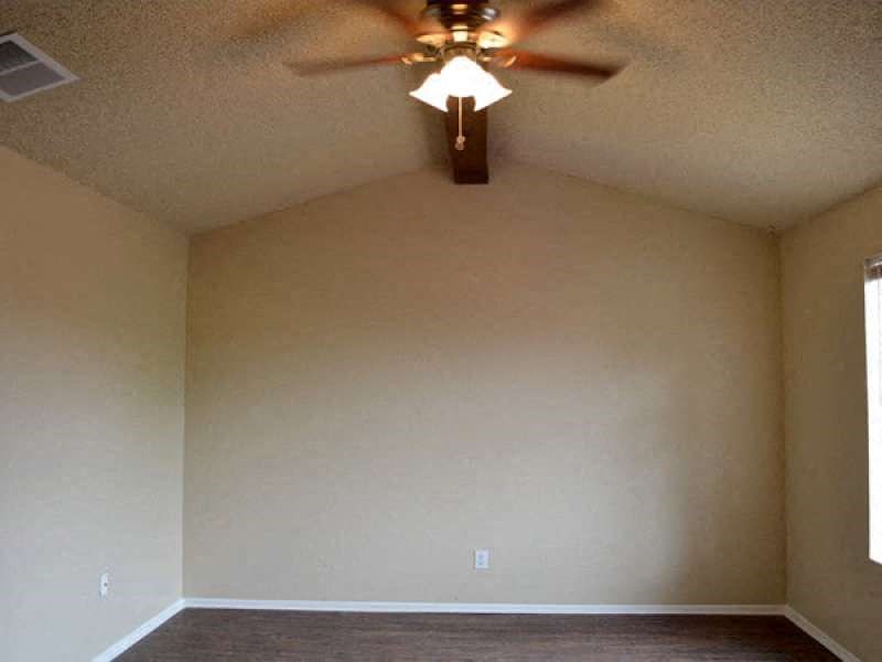 an empty living room with a ceiling fan