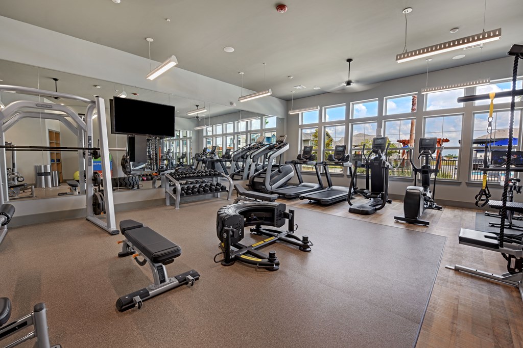 a gym with weights and cardio equipment and windows
