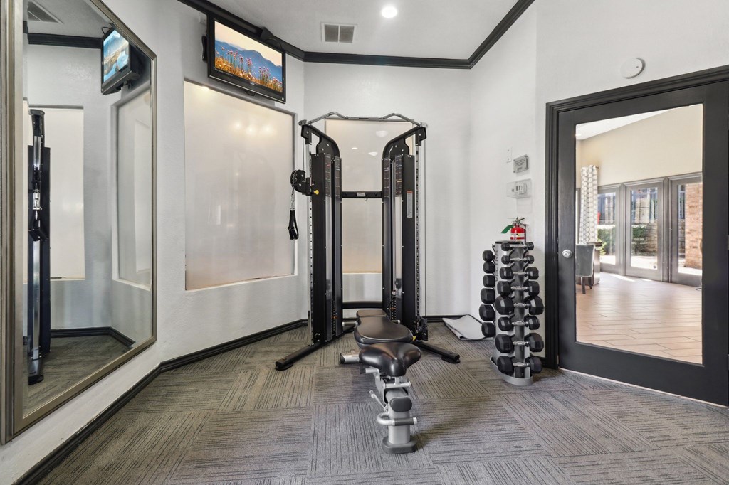 A gym with a row of treadmills and a television mounted on the wall.