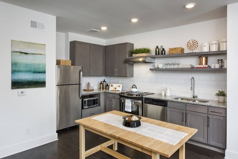 A modern kitchen with a wooden table and stainless steel appliances.