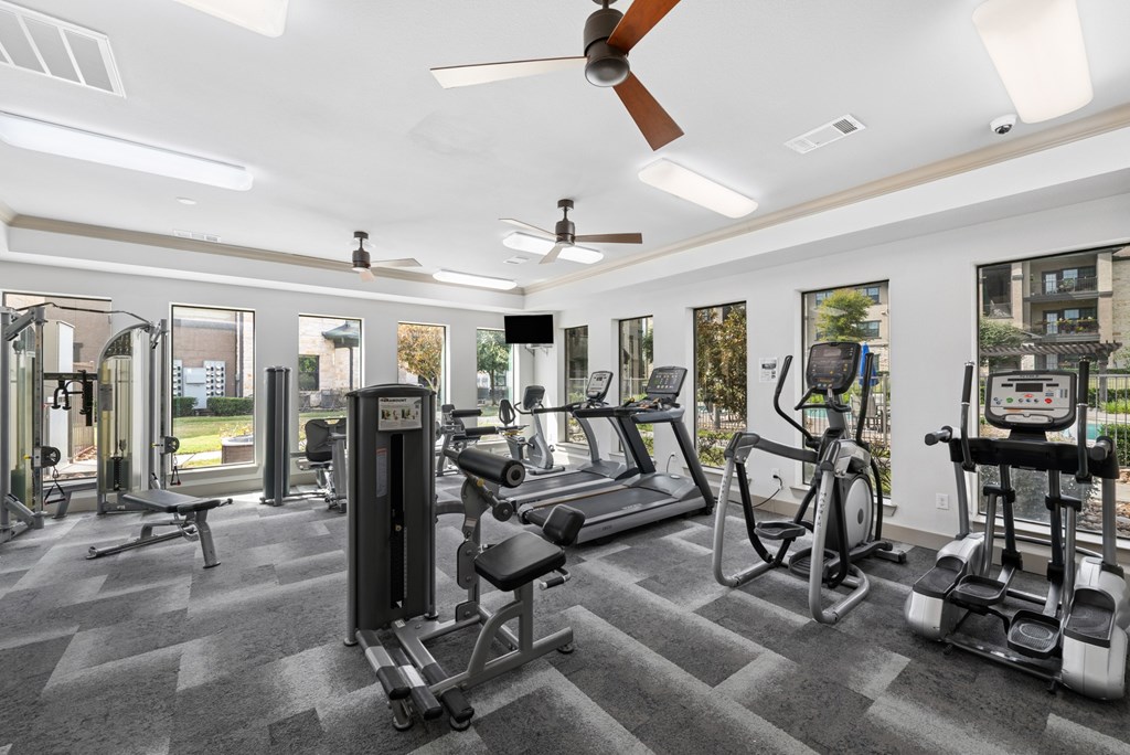 A gym with a variety of equipment including a treadmill, weights, and a stationary bike.