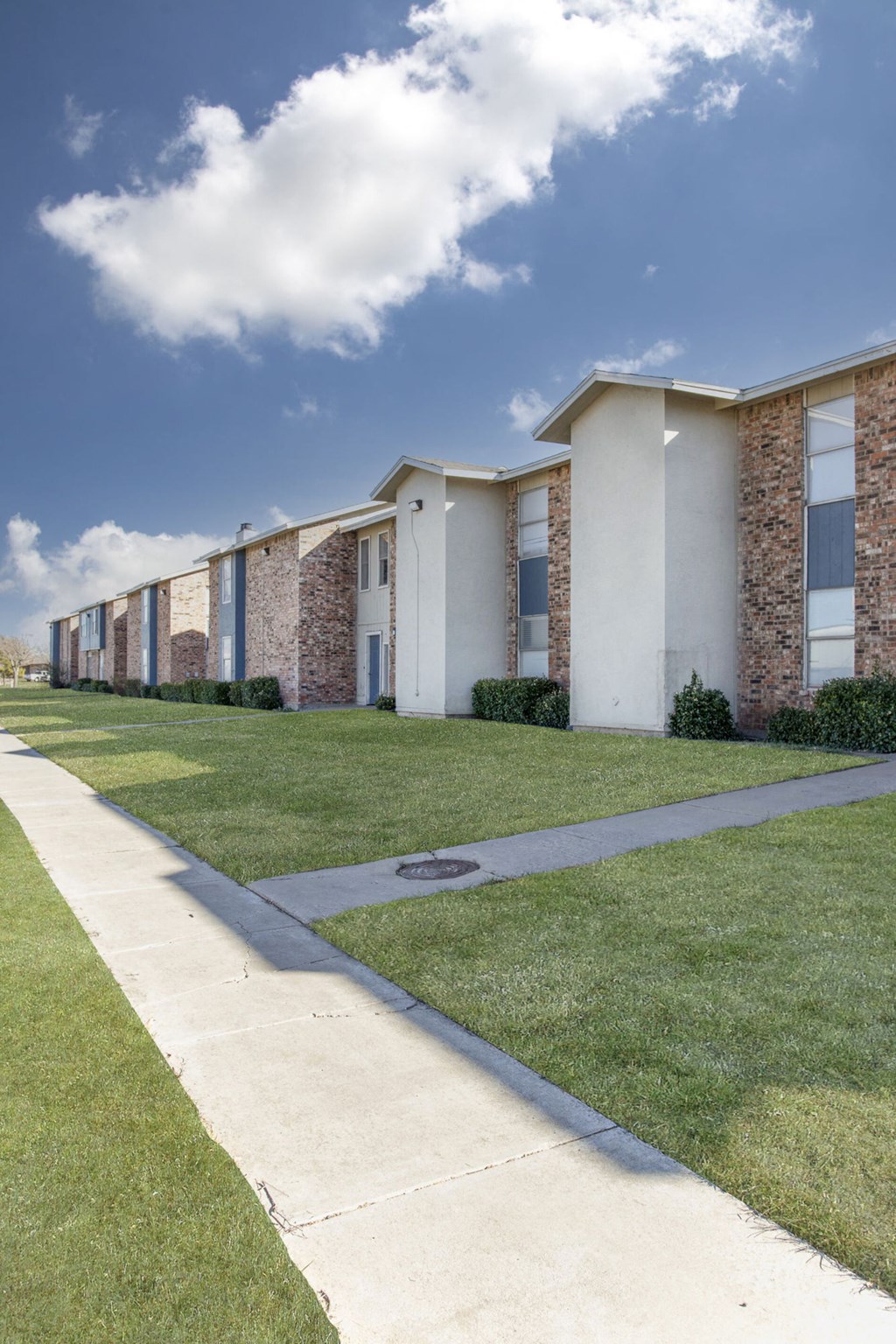 a row of buildings with grass and a sidewalk
