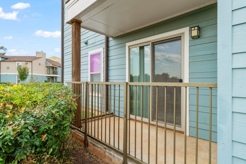A blue house with a white door and a window with a pink curtain.