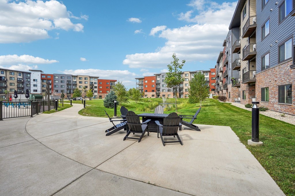 A patio with a table and chairs is surrounded by apartment buildings.