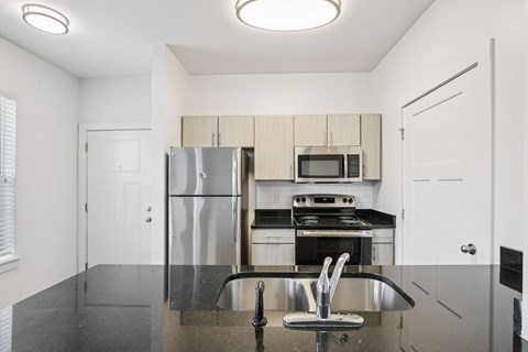A kitchen with a refrigerator, microwave, oven, and sink.