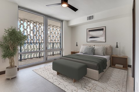 A bedroom with a large bed and a potted plant.