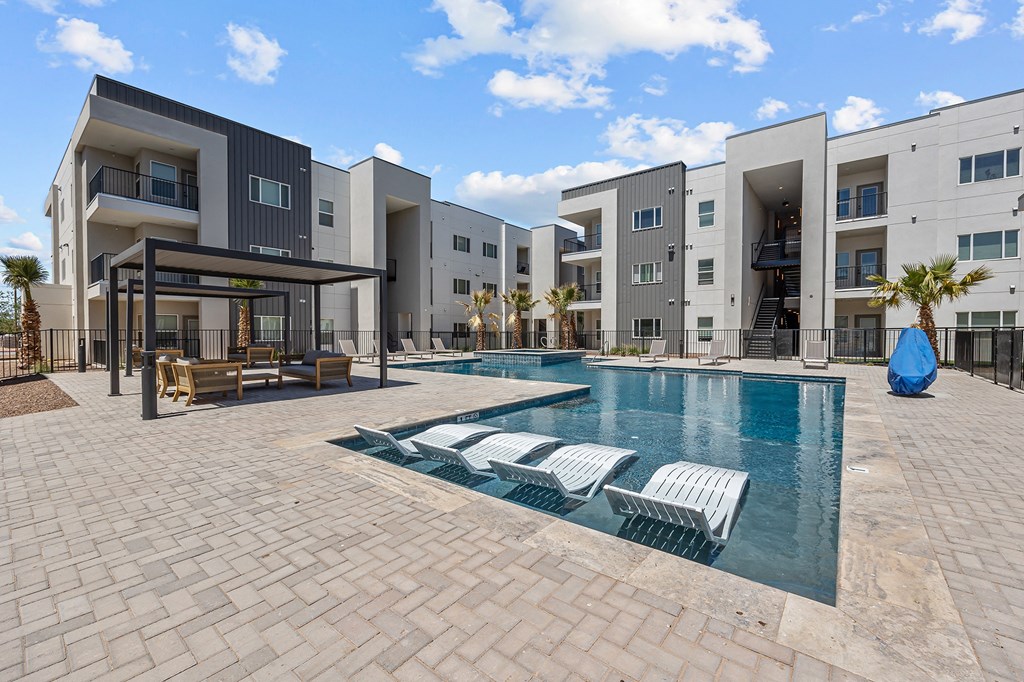 an apartment building with a pool and lounge chairs