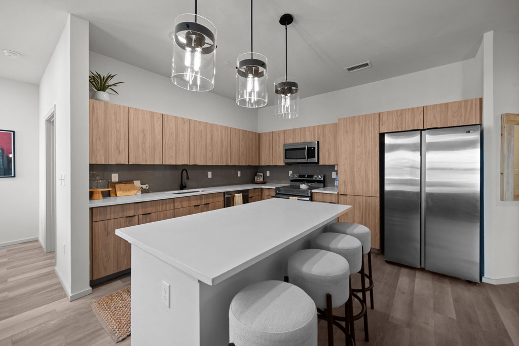 a kitchen with a large island and a stainless steel refrigerator