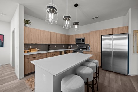 a kitchen with a large island and a stainless steel refrigerator