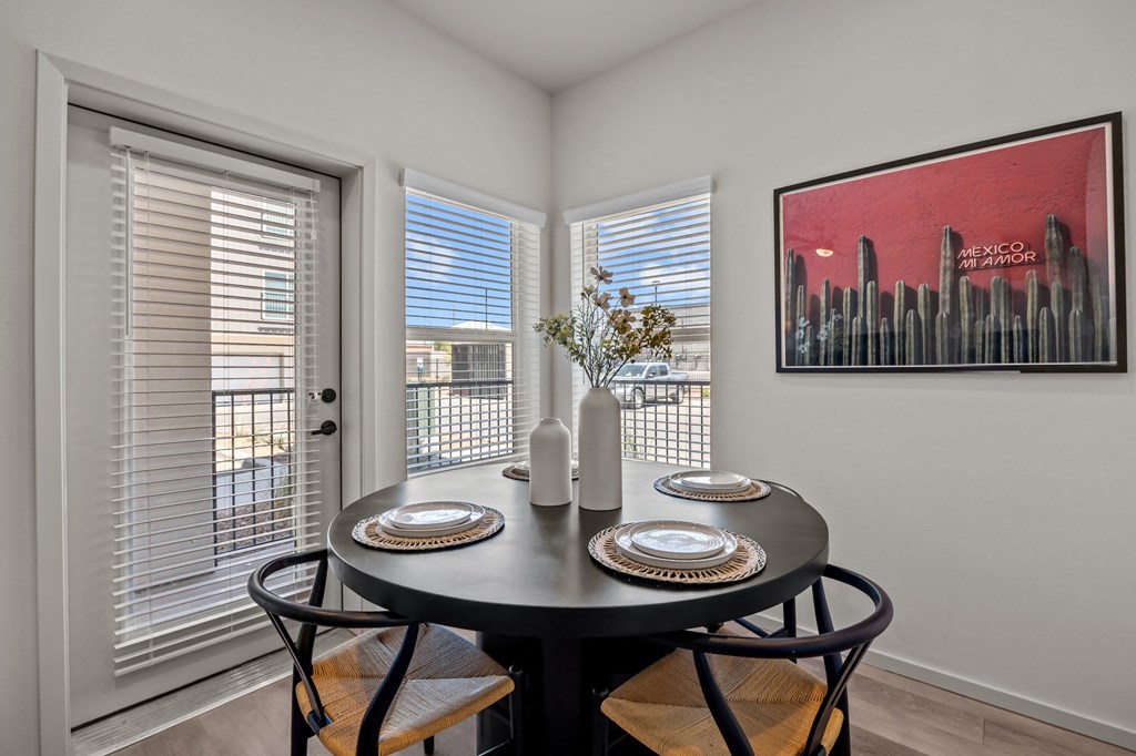 a dining room with three windows and a table with plates and chairs