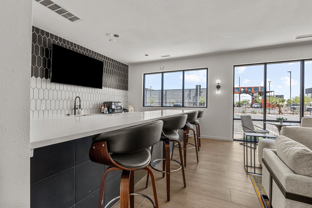 a bar with bar stools in a living room with a couch and a window