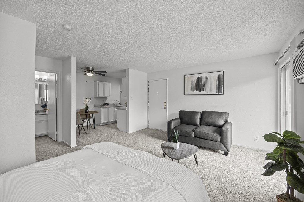 A living room with a grey couch and a white bedspread.