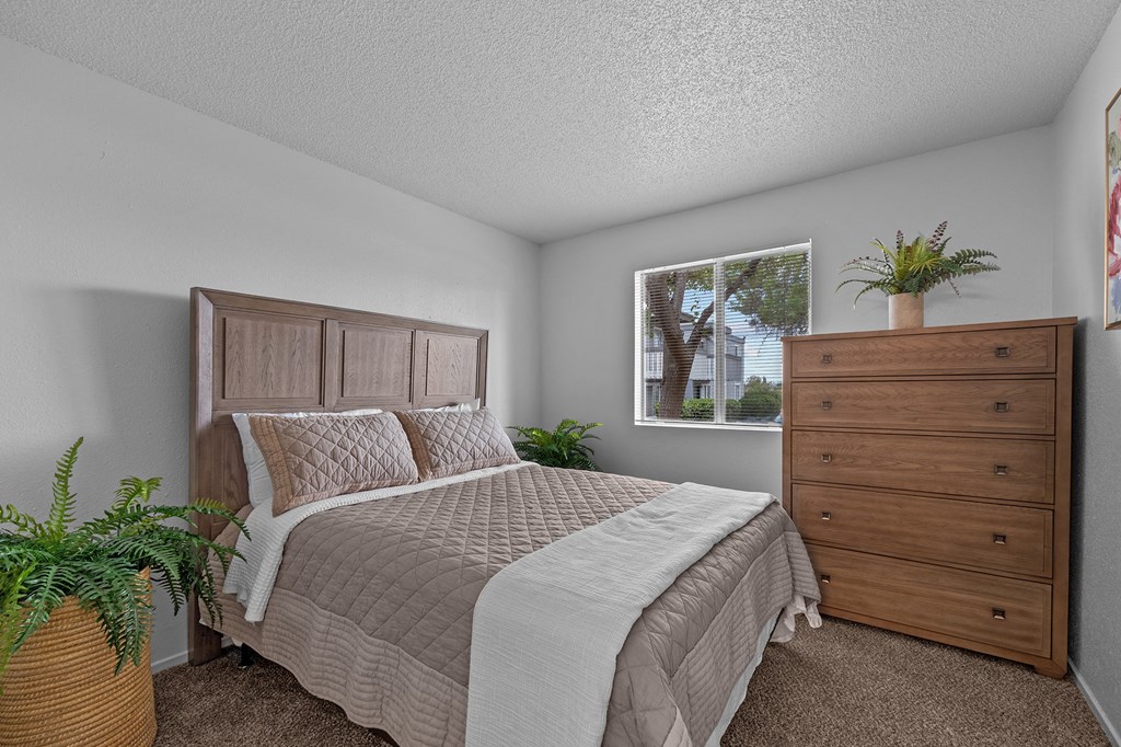 A bedroom with a bed, dresser, and window.