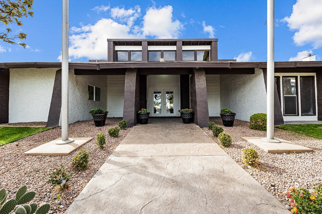 the front of a building with two pillars and a concrete walkway