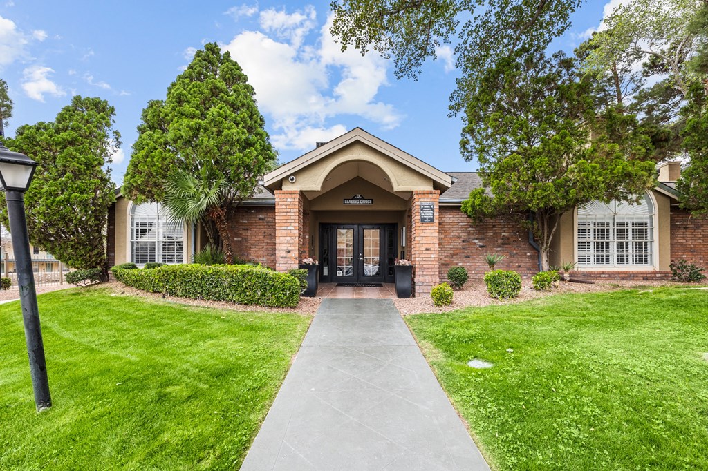 the front of a brick house with a sidewalk and grass