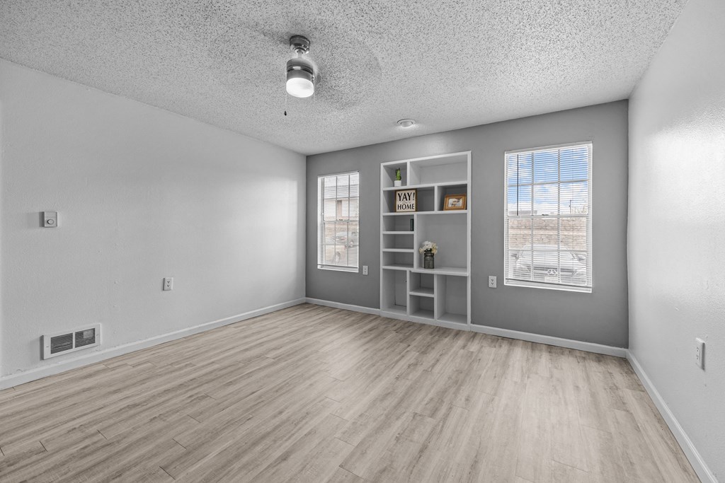 an empty living room with a bookshelf and a window