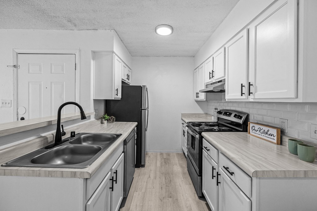 a kitchen with white cabinets and a sink and a refrigerator