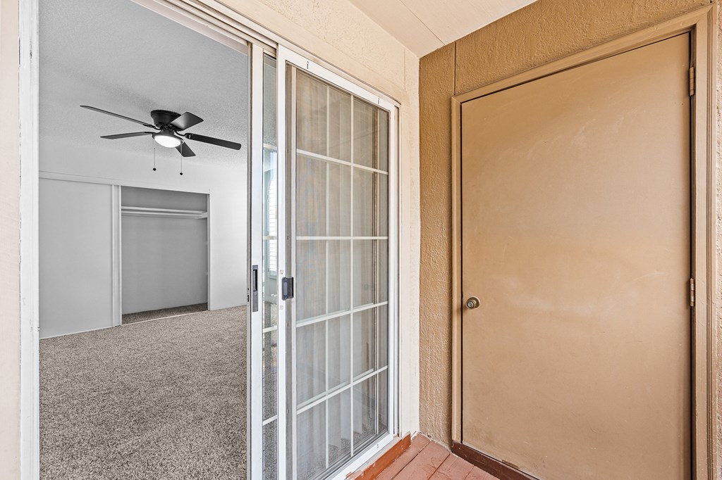 an empty room with a glass door and a ceiling fan