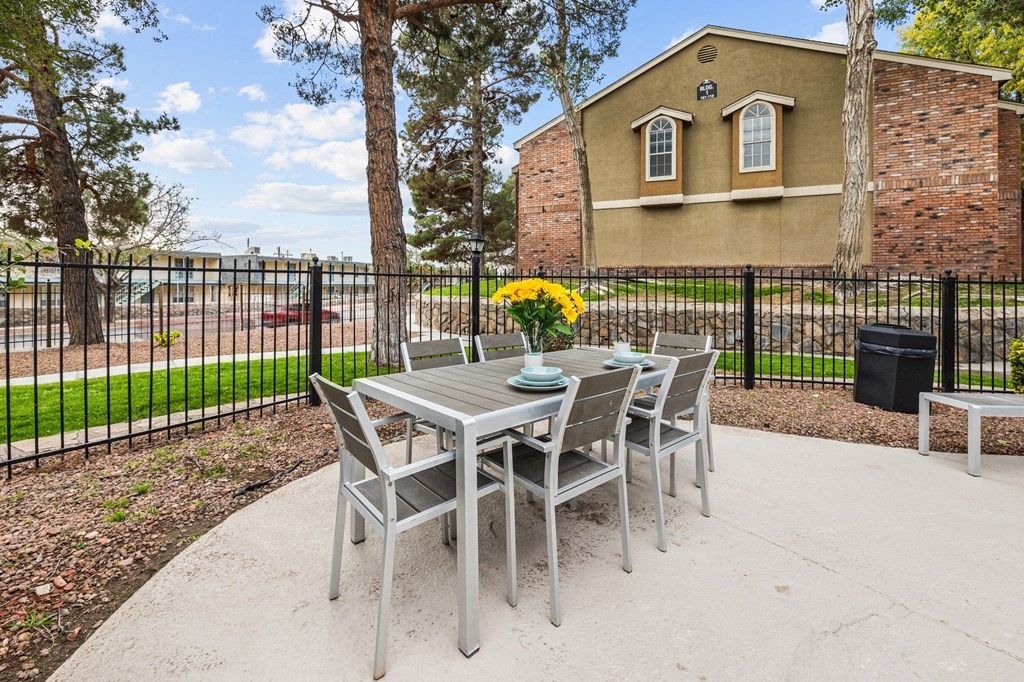 an outdoor patio with a table and chairs and a fence
